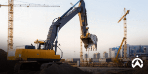 Yellow excavator at project site with GPS tracker for construction company to monitor heavy equipment at dusk.