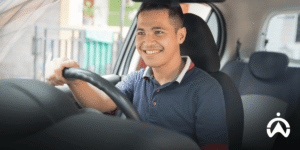 Sopir mengenakan polo biru mengendarai mobil