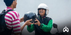Kurir motor mengenakan helm menerima perlengkapan dari rekan sebagai bentuk efisiensi operasional dalam bisnis dengan dukungan GPS tracker motor.
