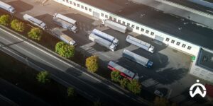 Aerial view of logistics trucks in a warehouse parking area managed using a SaaS fleet management system for operational efficiency.