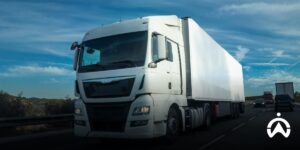 Truk putih besar melintasi jalan raya untuk pengelolaan armada kendaraan yang efisien dengan sistem manajemen logistik.