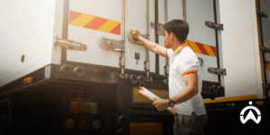 Petugas logistik memeriksa armada truk menggunakan Fleet Management System Cartrack Indonesia untuk kontrol biaya pengiriman.