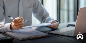 Staf meninjau dokumen administrasi di samping laptop untuk efisiensi fleet management system Cartrack bagi perusahaan.