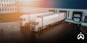 Two logistics trucks in the warehouse loading and unloading area using Cartrack Indonesia's Fleet Management System for fleet efficiency.