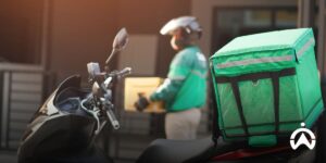 Kurir motor berseragam hijau membawa paket untuk identifikasi kebutuhan pemantauan sepeda motor sebelum pemasangan GPS tracker.