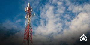 Red and white BTS tower under blue sky for illustration of BTS tower battery delivery optimization by PT Rajawali Prima Teknik.
