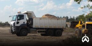 Truk kargo melintasi jalan raya di samping lahan pertanian luas