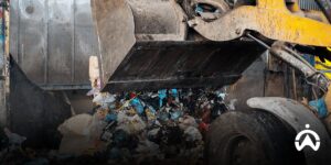 The yellow loader dumps B3 waste into an indoor collection area with the Cartrack GPS system.