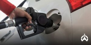 Pengemudi mengisi bensin mobil perak sebagai ilustrasi biaya operasional akibat perilaku mengemudi sopir yang tidak aman.