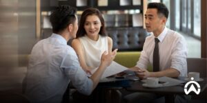Profesional sedang berdiskusi di kafe mengenai keuntungan menggunakan GPS tracker dengan sistem berlangganan untuk manajemen armada.