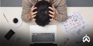 A person is stressed at a desk with a laptop