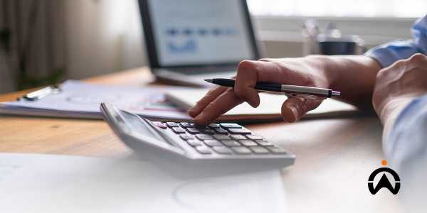 A person uses a calculator and laptop to calculate fuel consumption in a company fleet.