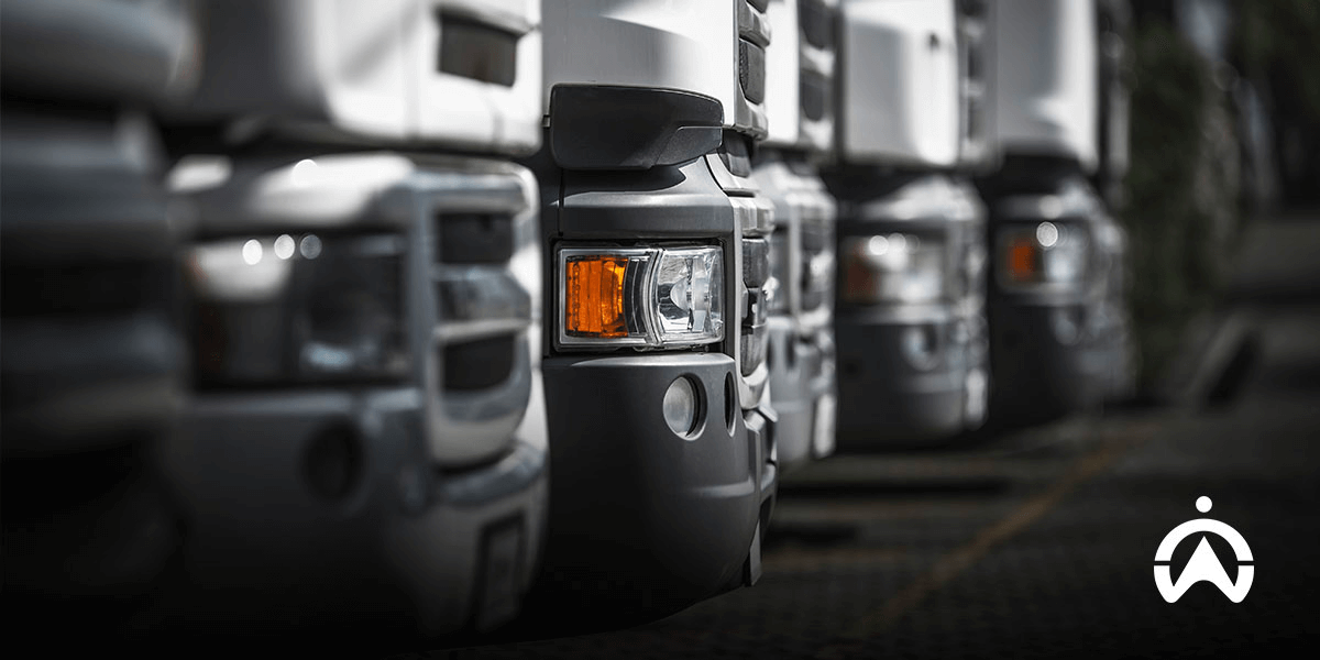 Barisan lampu depan dan bumper truk putih yang diparkir rapi, menggambarkan pentingnya SOP manajemen armada dalam operasional