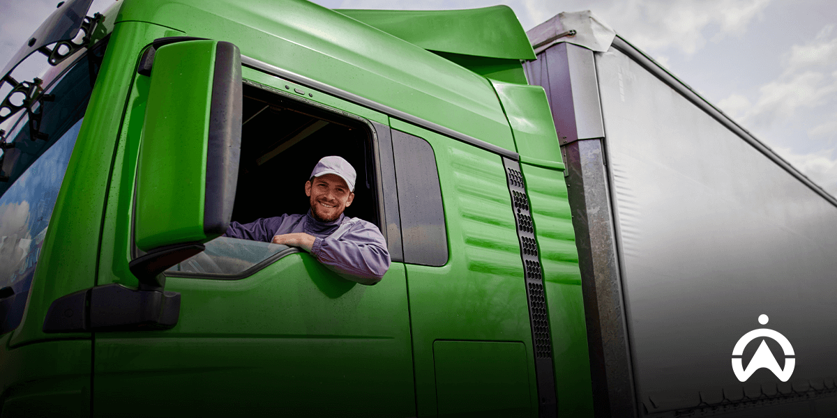 Sopir tersenyum di jendela truk hijau, siap menerapkan manajemen armada hijau dengan truk listrik.