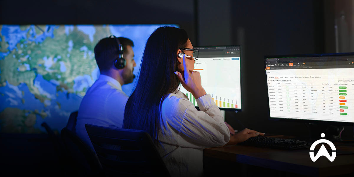 Dua petugas call center memantau data peta di komputer untuk komunikasi dispatcher dan pengemudi yang efektif.