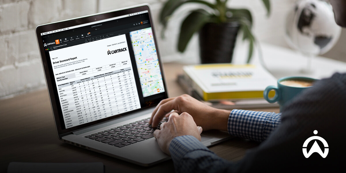 Seseorang mengetik di laptop yang menampilkan driver scorecard Cartrack untuk analisis pelatihan pengemudi.