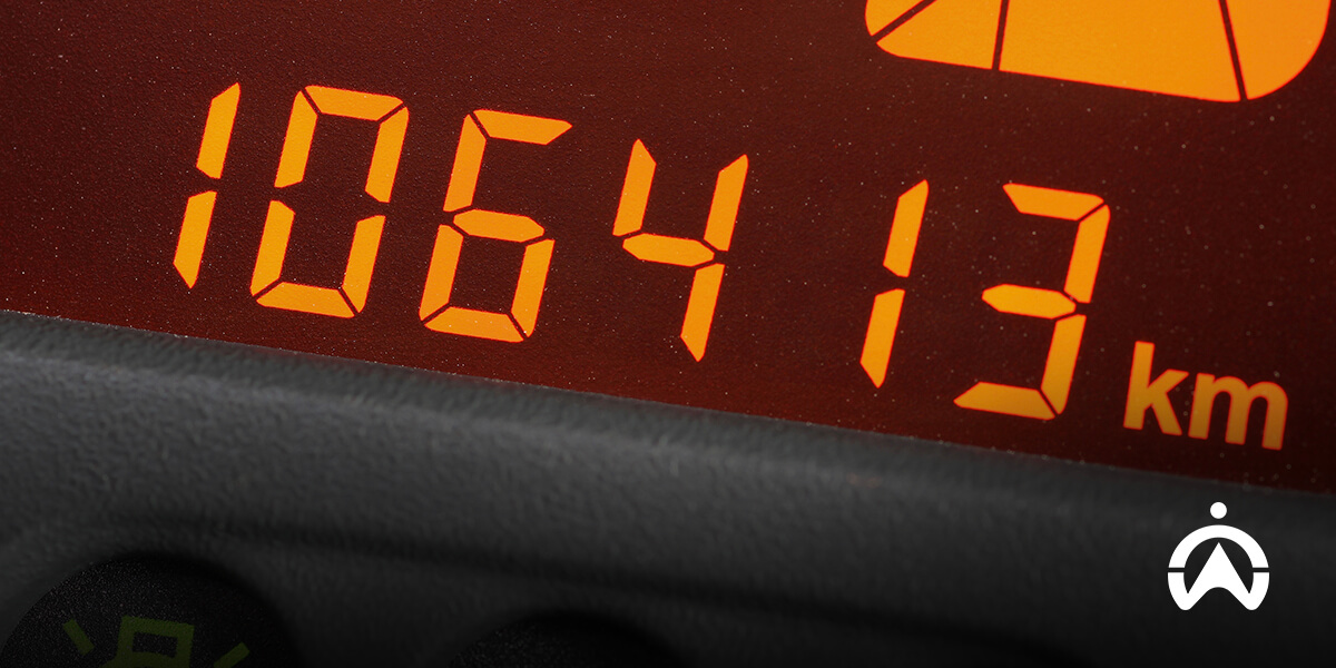Tampilan dekat odometer mobil yang menunjukkan angka 106413 km dengan angka berwarna oranye terang pada latar belakang gelap.