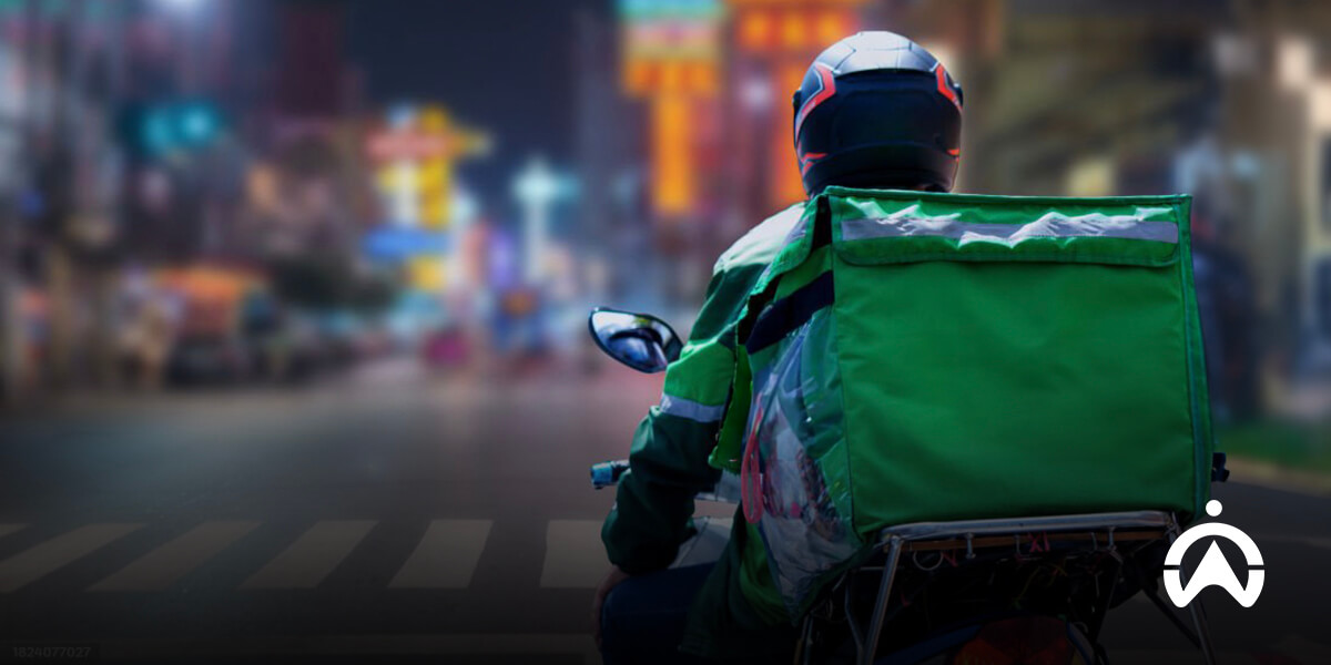 Kurir mengendarai sepeda motor membawa tas pengantar barang untuk layanan bisnis delivery.