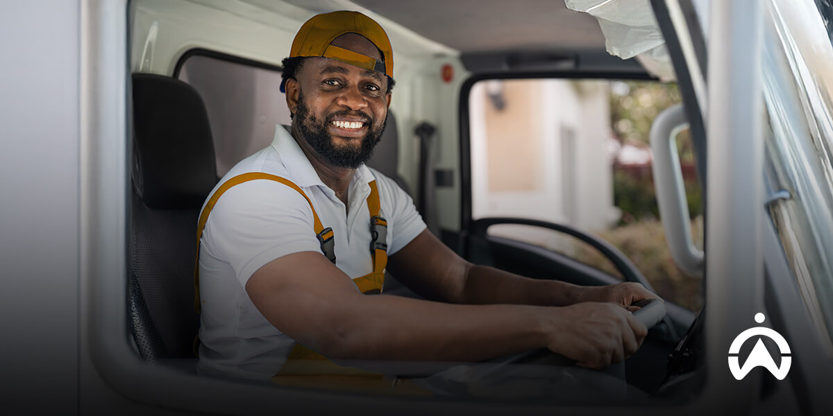 Pengemudi mengoperasikan truk armada bisnis dengan sistem fleet management untuk memantau perjalanan.