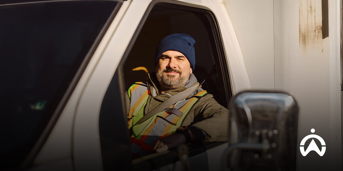 A person in a high-visibility vest sitting inside a vehicle cabin.