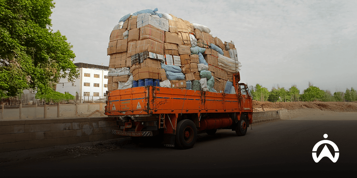 Truk oranye mengalami overload akibat muatan barang berlebih di jalan raya.