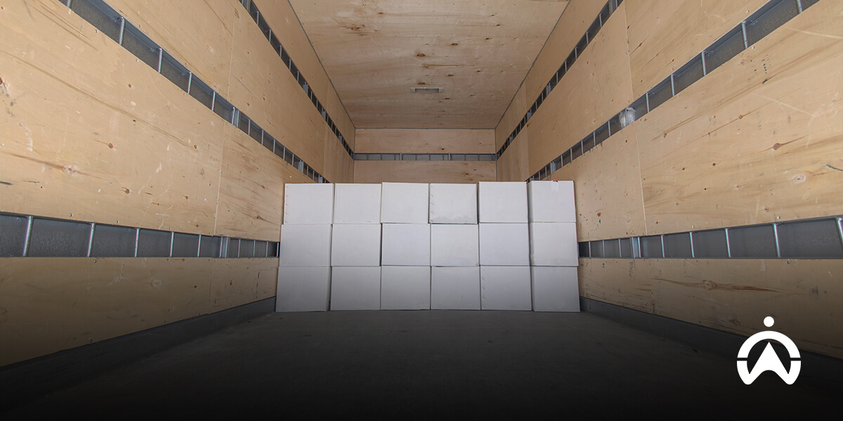 Empty wooden truck trailer interior with stacks of white cardboard boxes for large scale freight shipments using FTL or LTL methods.