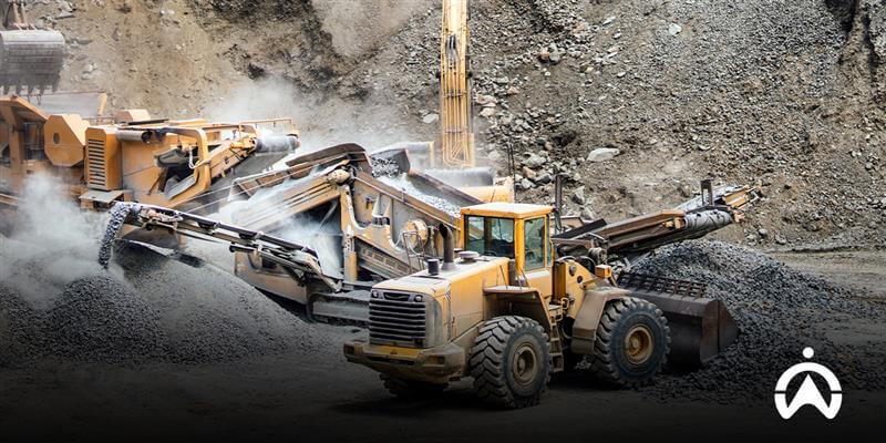 A yellow front loader type heavy equipment is moving gravel in the mining area based on its function.